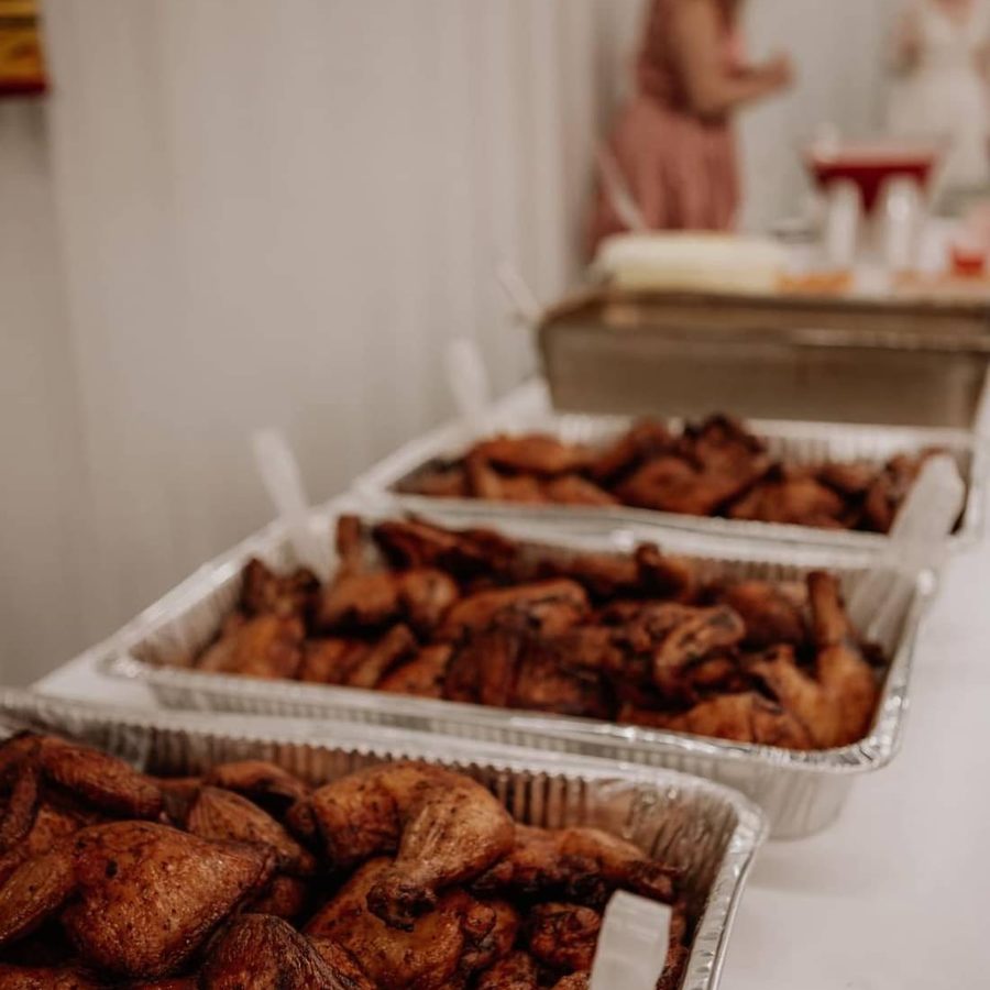 Catering pans of smoked chicken lined up at an event